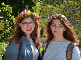 Zwei Parkbesucherinnen mit Blumenkränzen auf dem Kopf, die in die Kamera lächeln